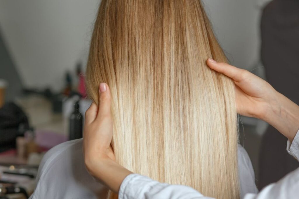 Capelli biondi lisci e luminosi visti di spalle, dopo un trattamento tonalizzante