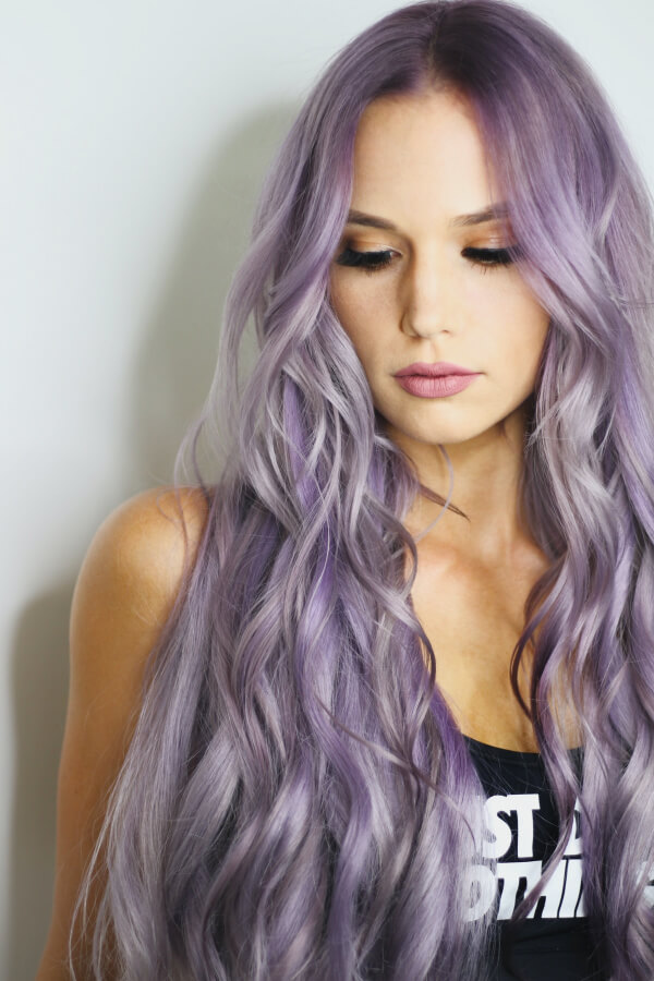 Donna con capelli lunghi mossi color lilla e grigio perla, risultato di un trattamento colore in salone